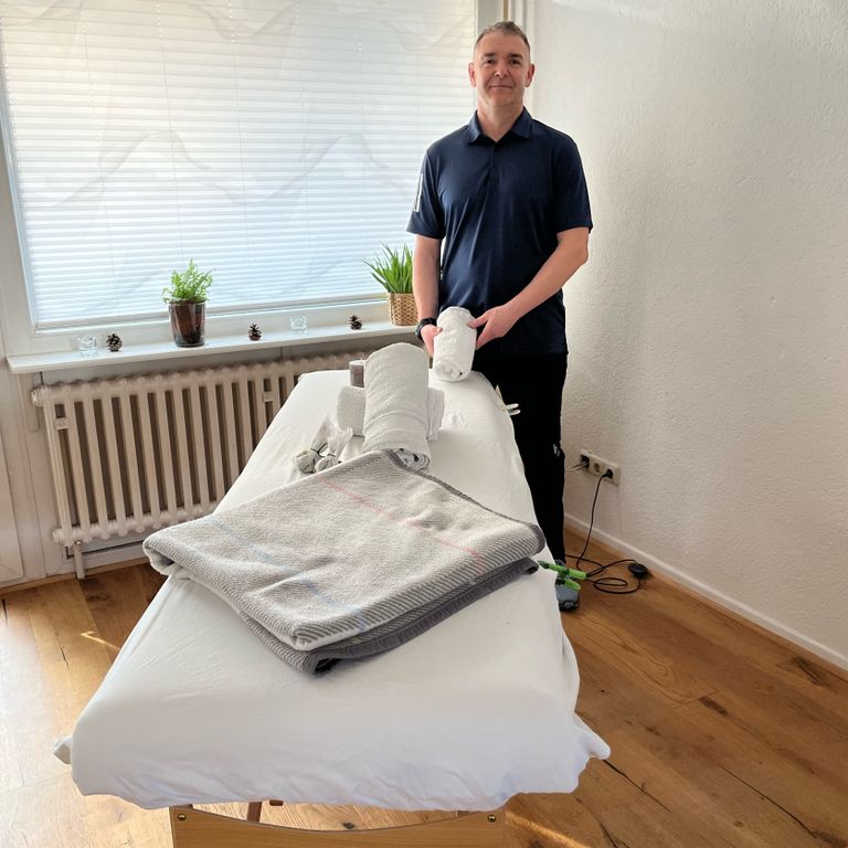 Peter hinter einer Massageliege in entspannter Umgebung